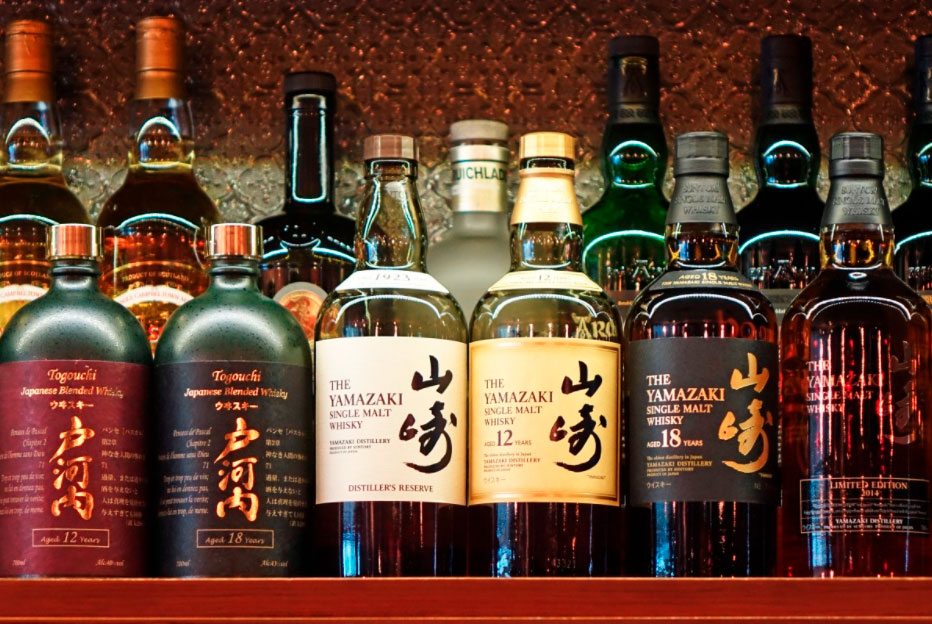 muchas botellas de whisky japonés en un mueble