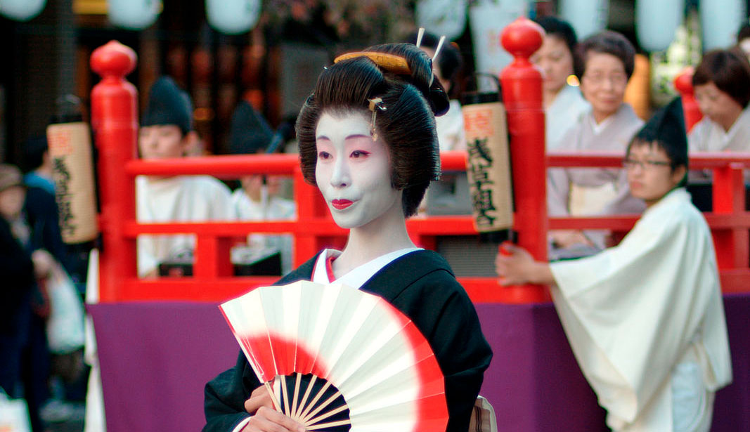 geisha posando en un festival en Japón con un abanico