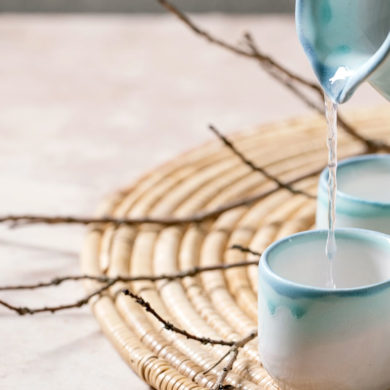 jarra sirviendo sake sobre un vaso de cerámica